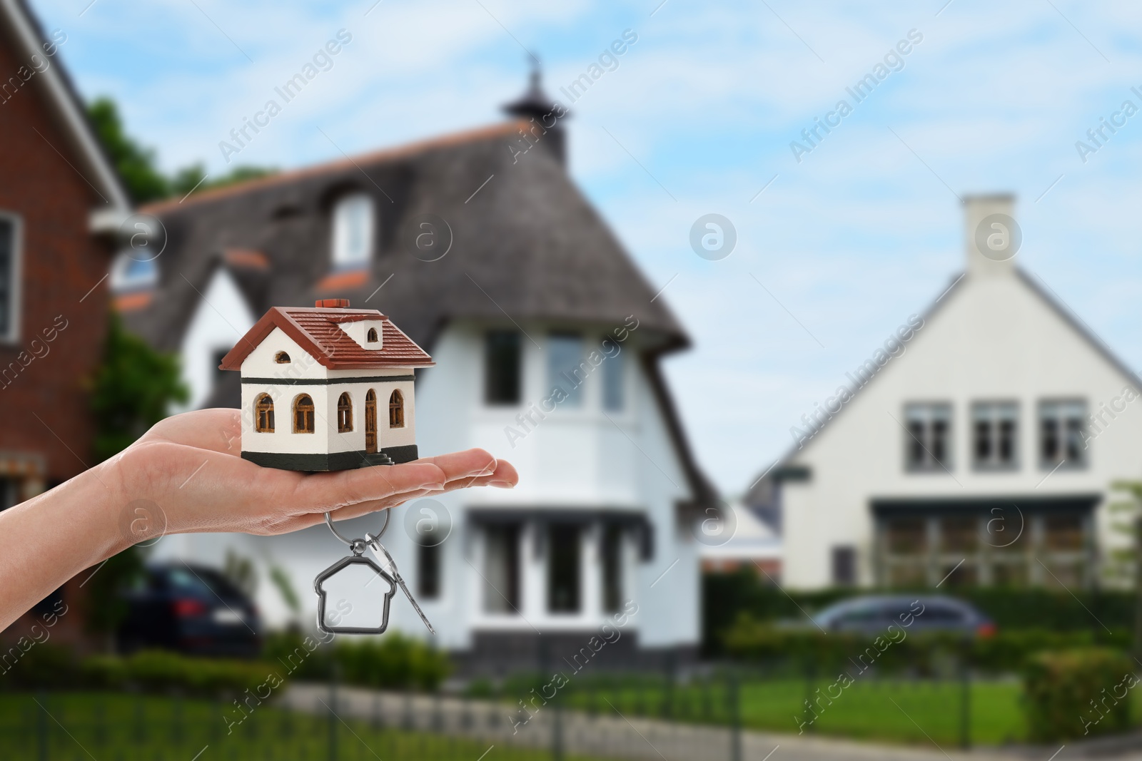 Image of Real estate agent holding house model and key against future dwelling, closeup