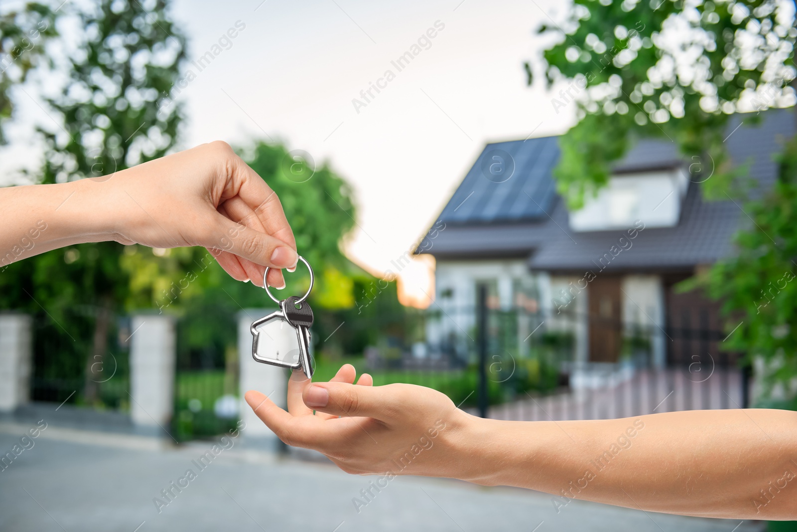 Image of Real estate agent giving house key to new owner against beautiful dwelling, closeup