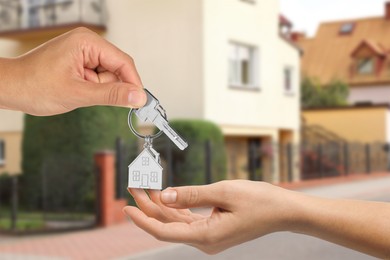 Image of Real estate agent giving house key to new owner against beautiful dwelling, closeup