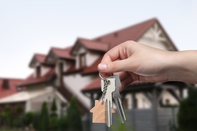 Image of Real estate agent holding keys against beautiful house, closeup