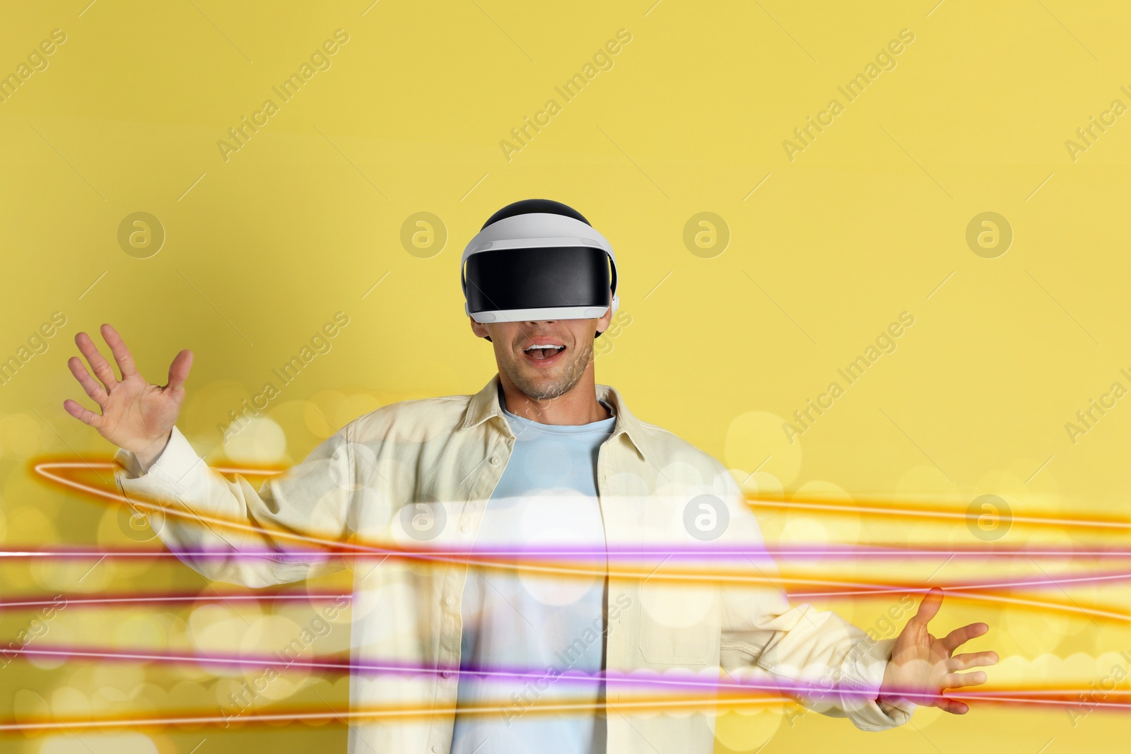 Image of Man using virtual reality headset on yellow background. Modern technology. Bright lines around him