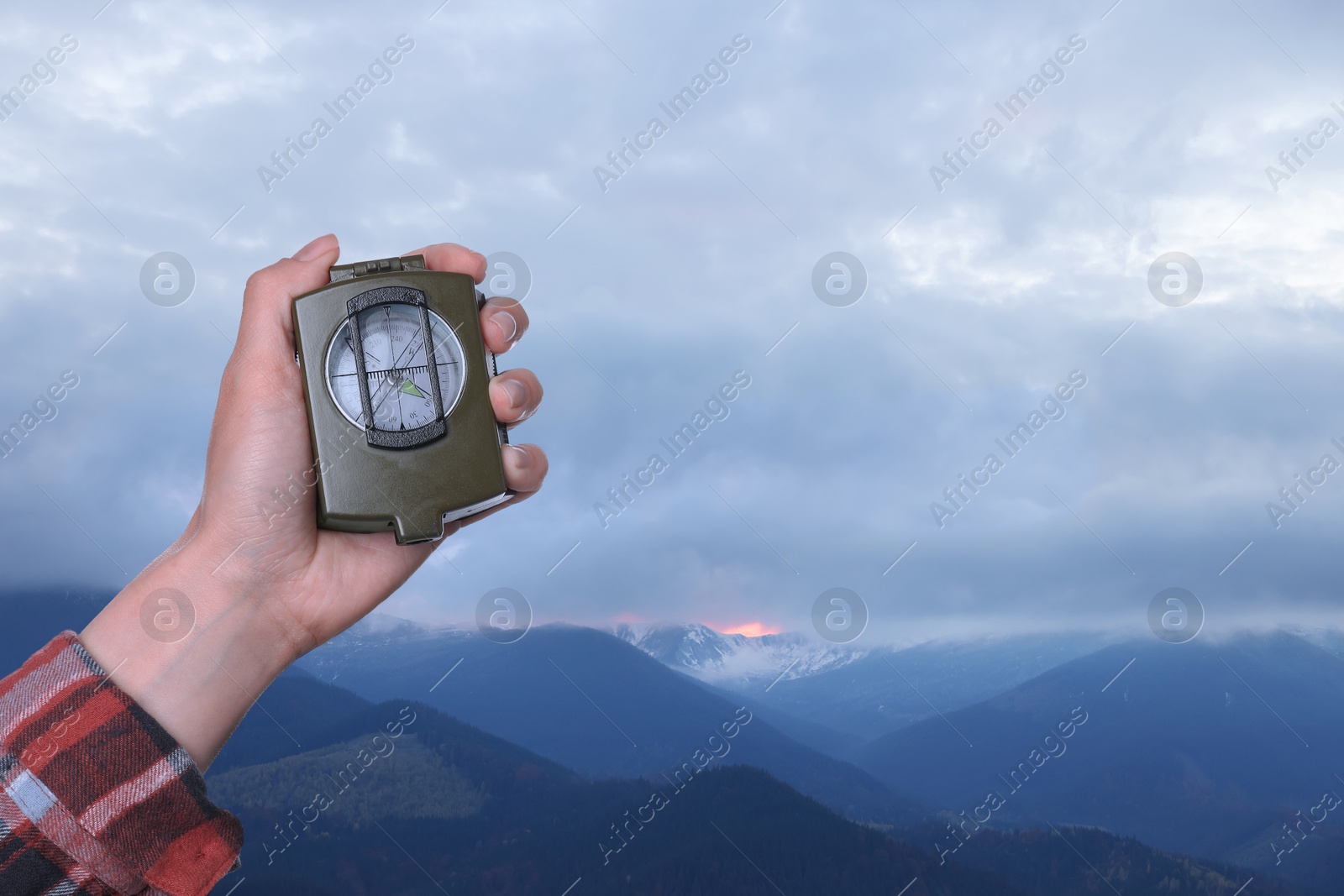 Image of Woman using compass in mountains, closeup. Navigational instrument