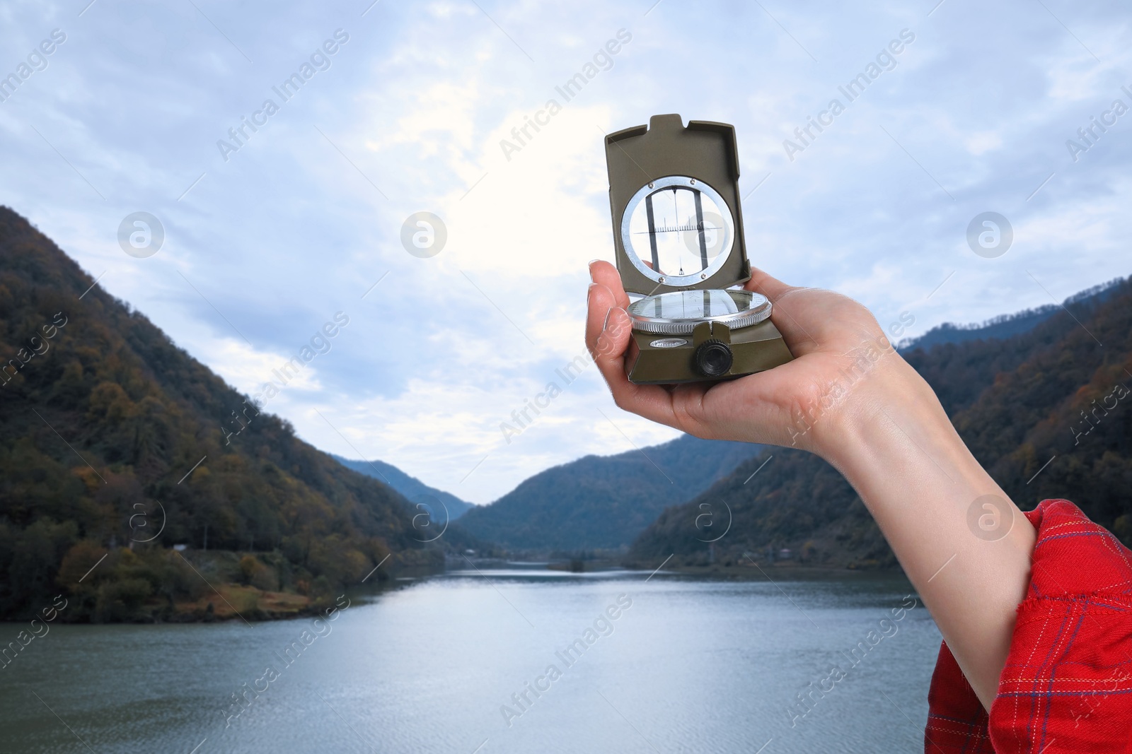 Image of Woman using compass in mountains, closeup. Navigational instrument