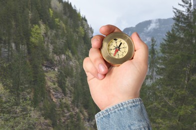 Image of Man using compass in mountains, closeup. Navigational instrument