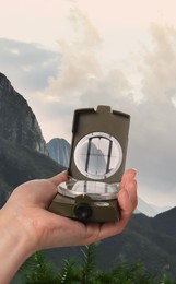 Image of Woman using compass in mountains, closeup. Navigational instrument