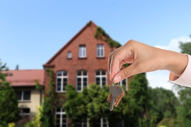 Image of Real estate agent holding house key against beautiful dwelling, closeup