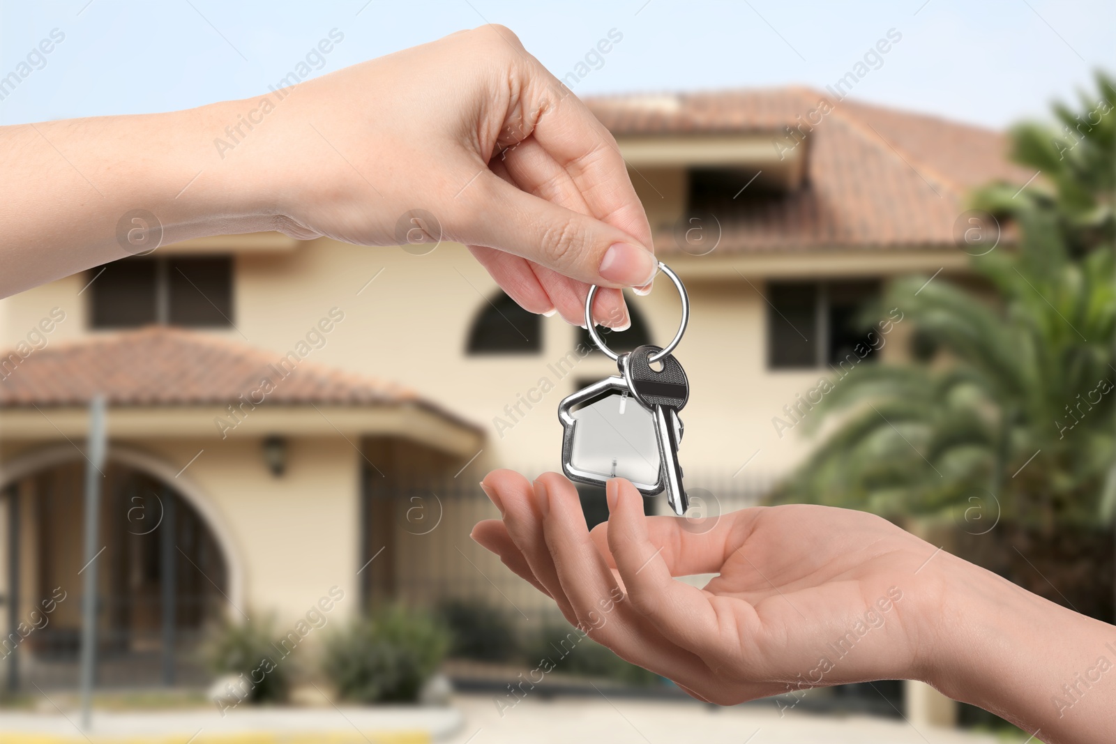 Image of Real estate agent giving house key to new owner against beautiful dwelling, closeup