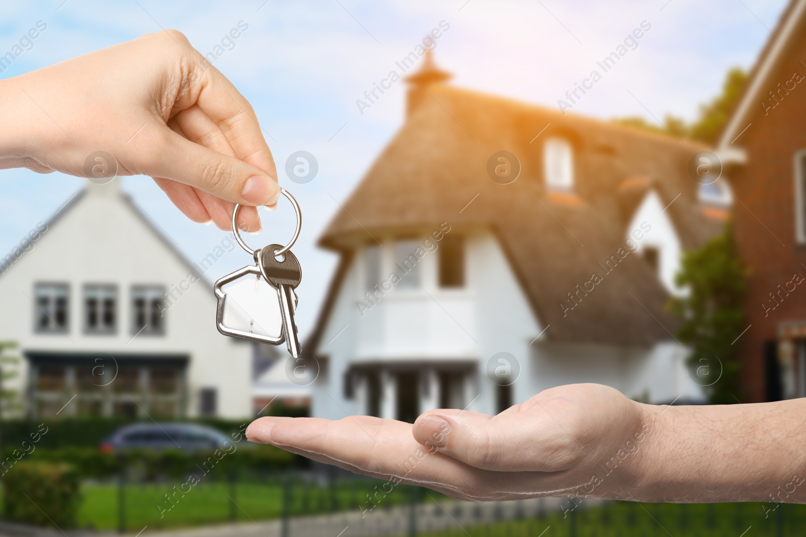 Image of Real estate agent giving house key to new owner against beautiful dwelling, closeup