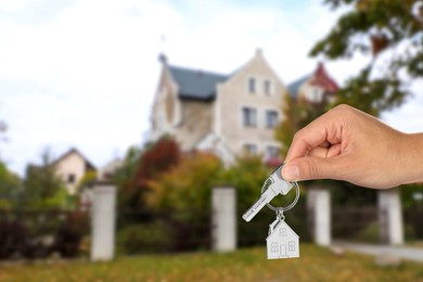 Image of Real estate agent holding house key against beautiful dwelling, closeup