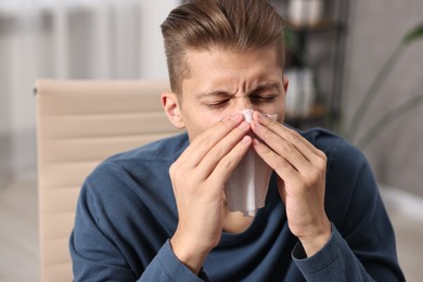 Photo of Young man with tissue suffering from sinusitis indoors