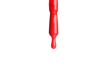 Photo of Red nail polish dripping from brush isolated on white