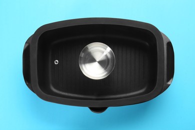 Photo of Black pot with lid on light blue background, top view