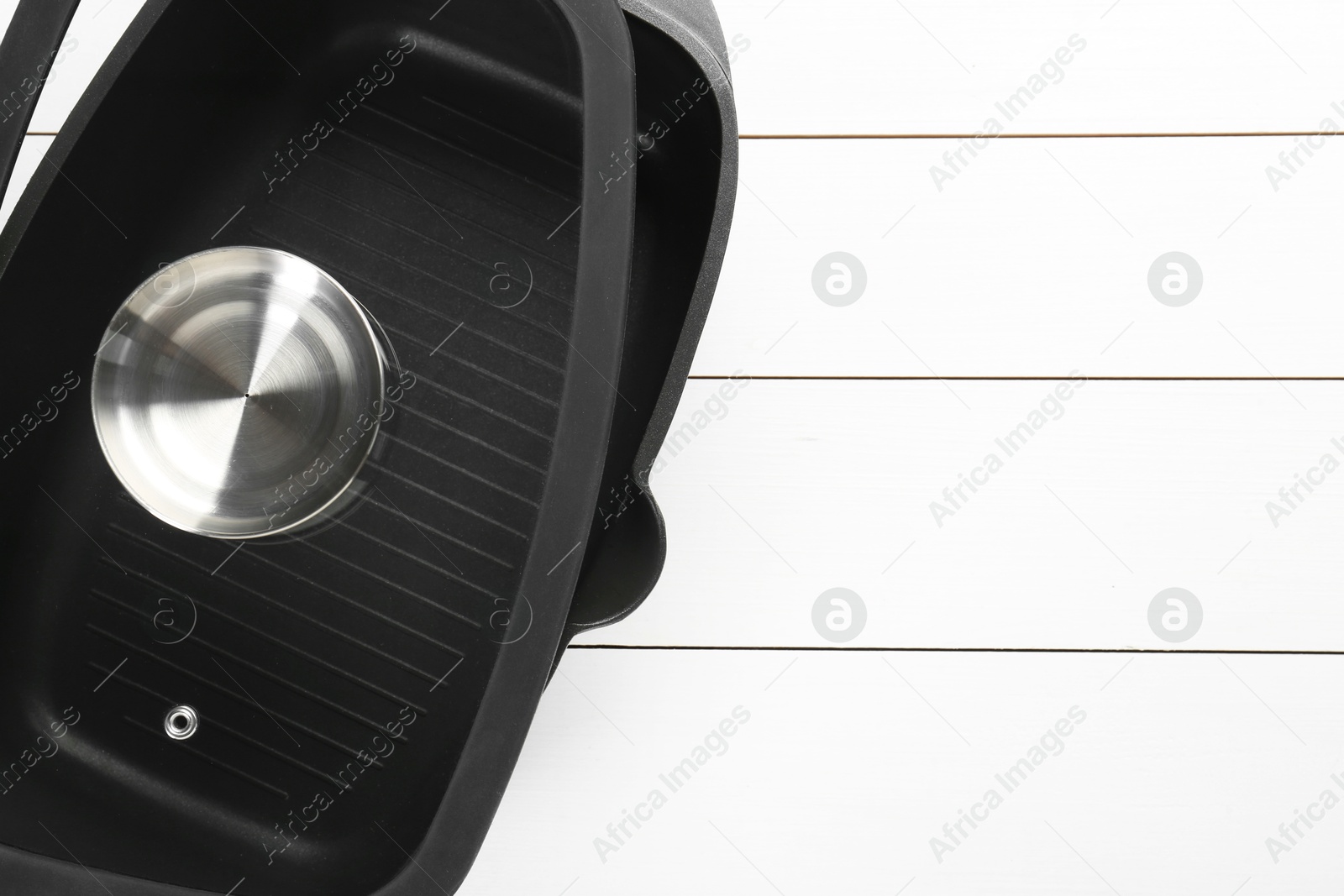 Photo of Black pot with lid on white wooden table, top view. Space for text