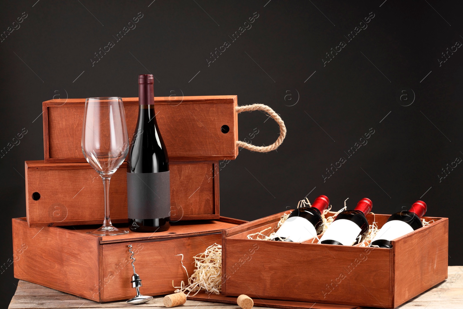 Photo of Boxes with wine bottles and glass on wooden table against black background