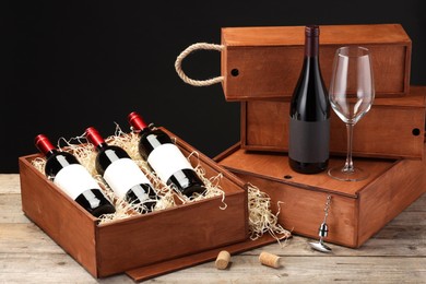 Photo of Boxes with wine bottles and glass on wooden table against black background