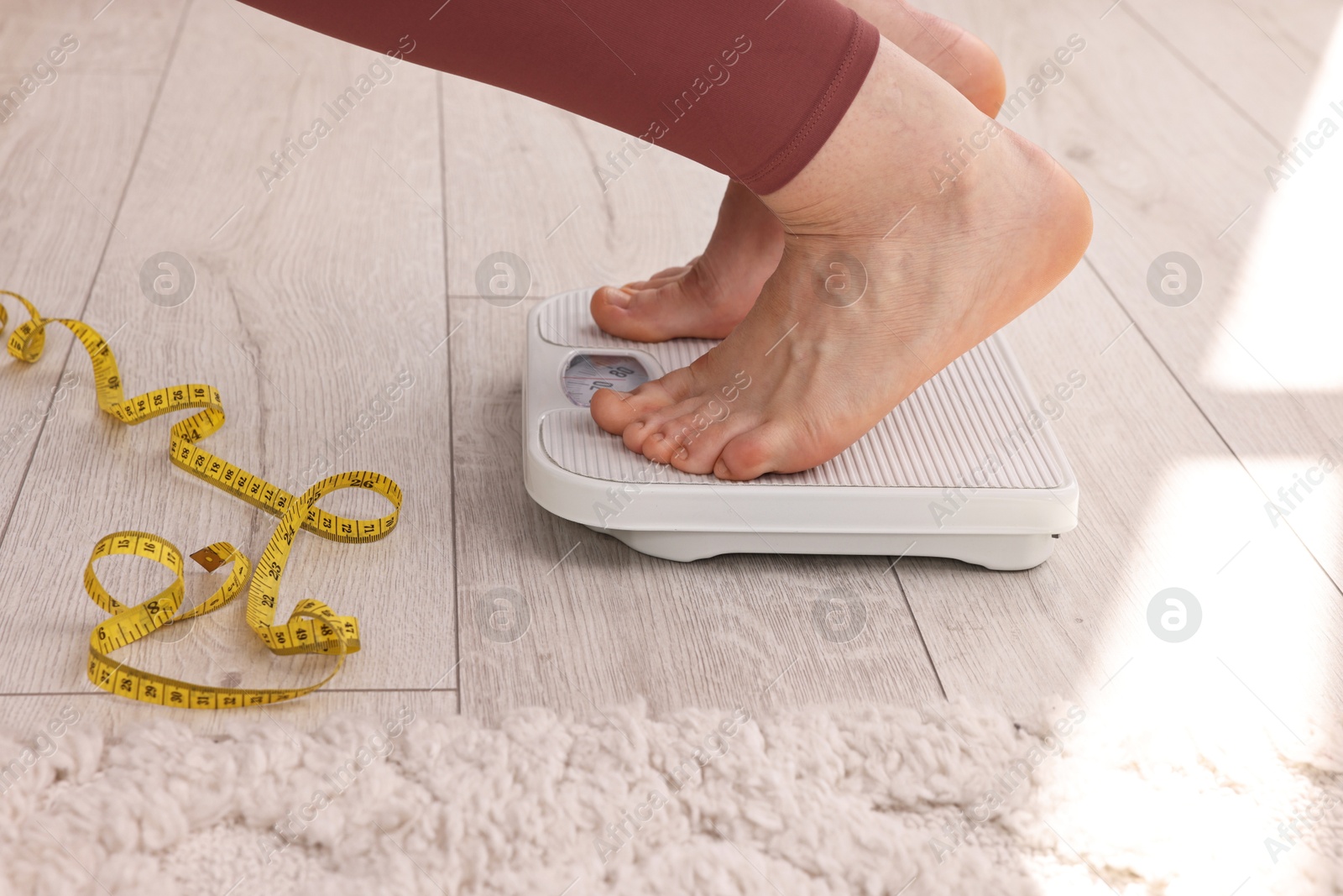 Photo of Woman on floor scale and measuring tape at home, closeup. Weight control