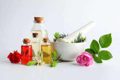 Photo of Aromatherapy. Different essential oils, flowers, mortar, pestle and fir twigs on white background