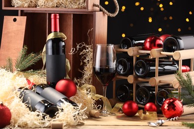 Photo of Bottles of wine, glass, wooden box, corks and red Christmas balls on table
