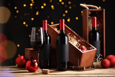 Photo of Bottles of wine, glass, wooden boxes, corkscrew and red Christmas balls on table