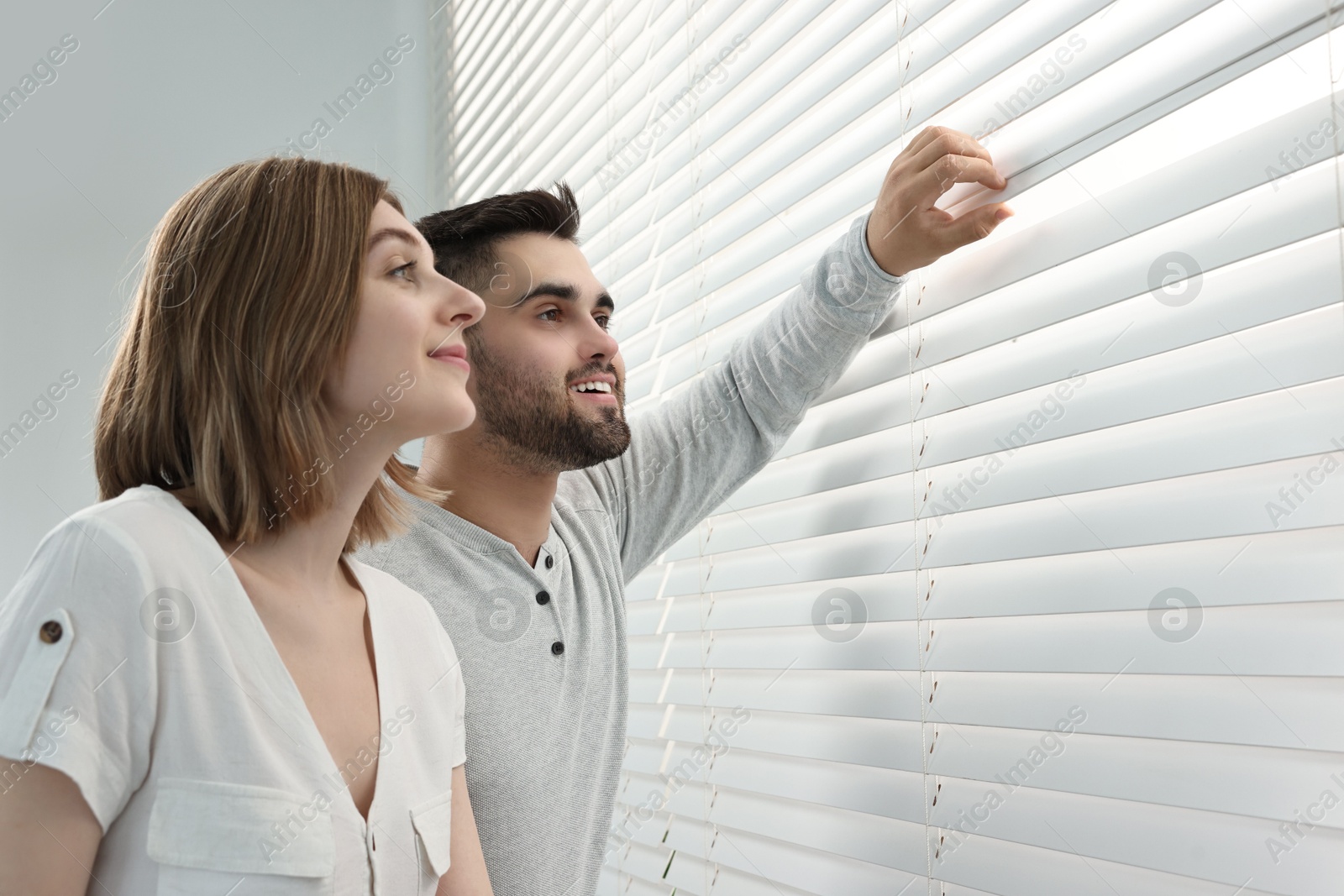 Photo of Young couple near window blinds at home