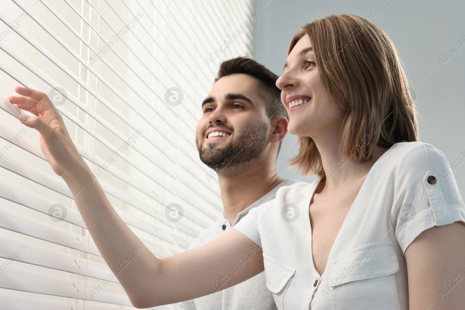 Photo of Young couple near window blinds at home