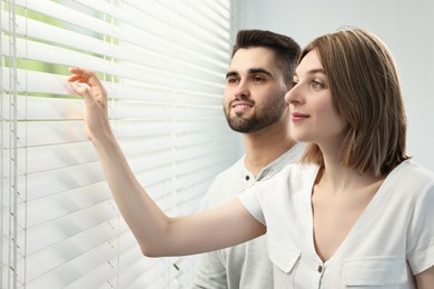 Photo of Young couple near window blinds at home