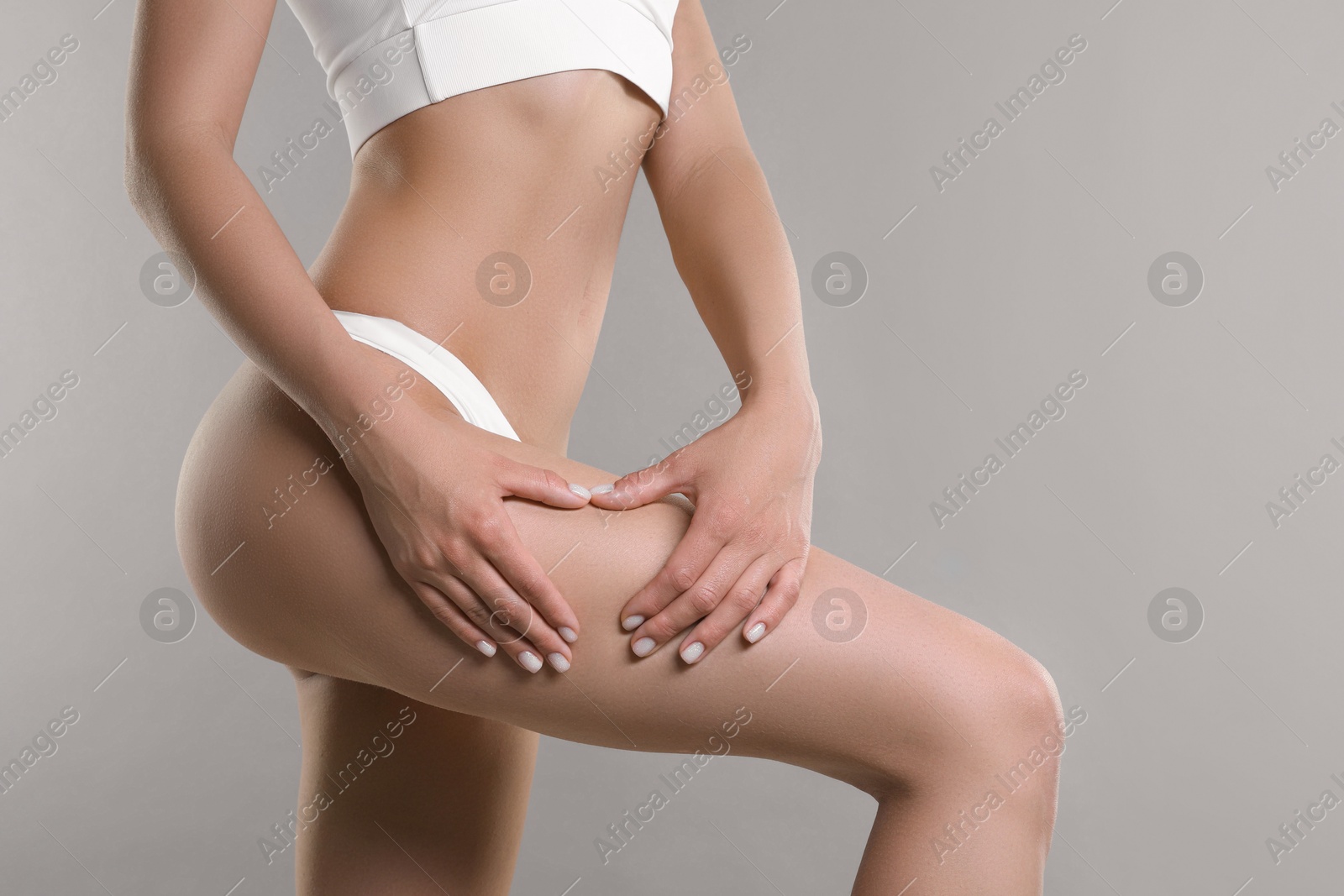 Photo of Woman in underwear making heart with hands near thigh on light grey background, closeup. Cellulite problem