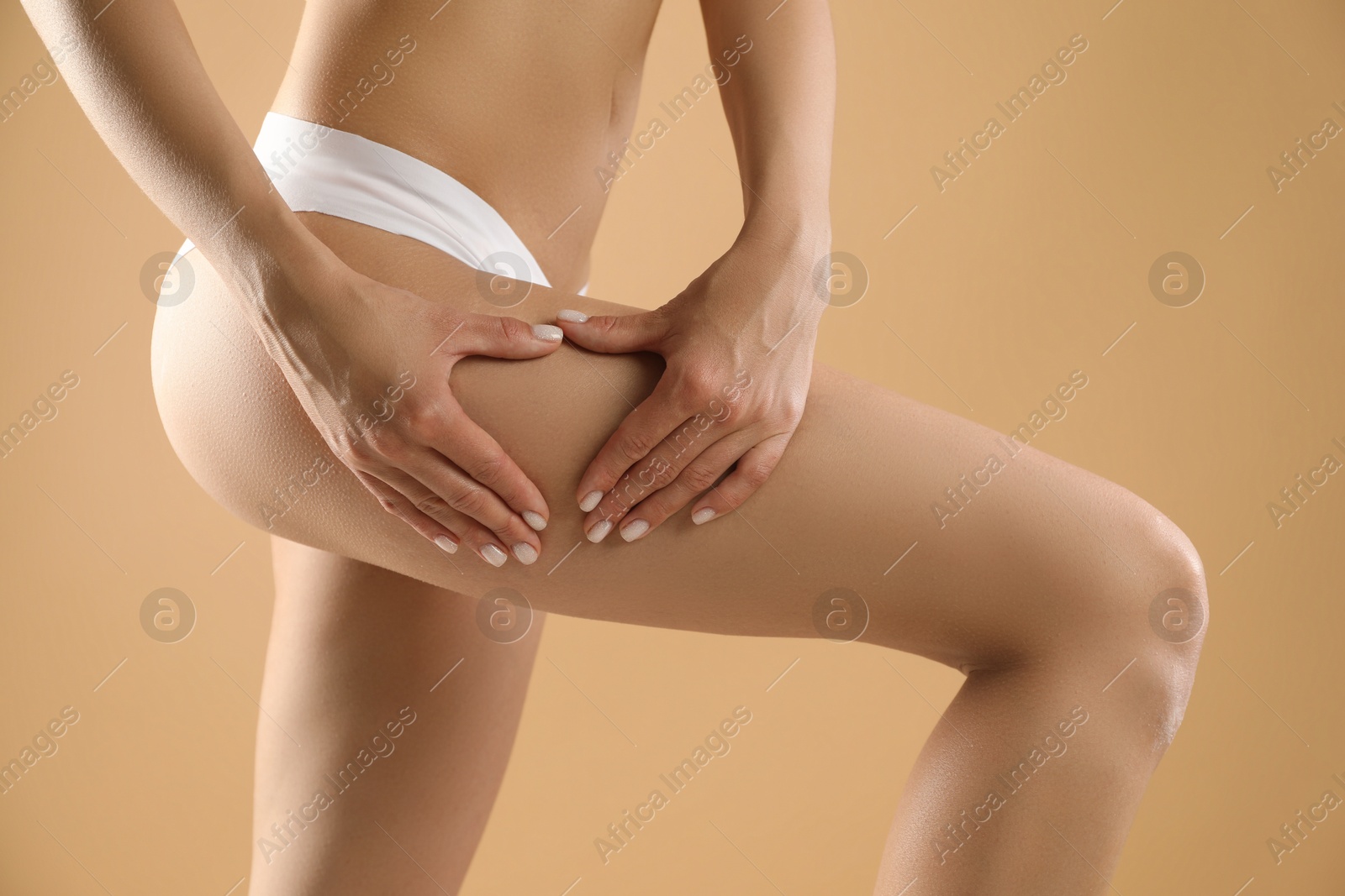 Photo of Woman in underwear making heart with hands near thigh on beige background, closeup. Cellulite problem