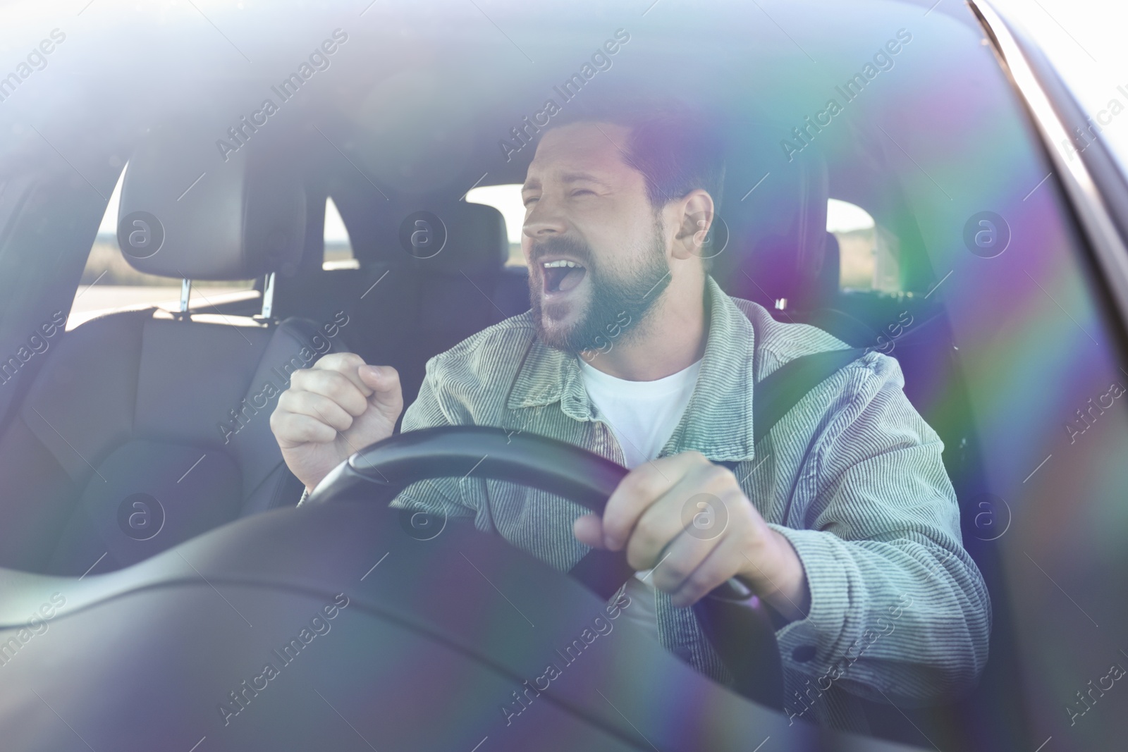 Photo of Man singing in car, view through windshield