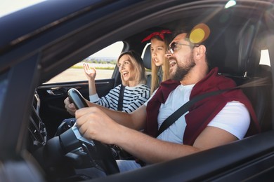 Photo of Happy family singing in car, view from outside