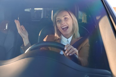 Woman singing in car, view through windshield