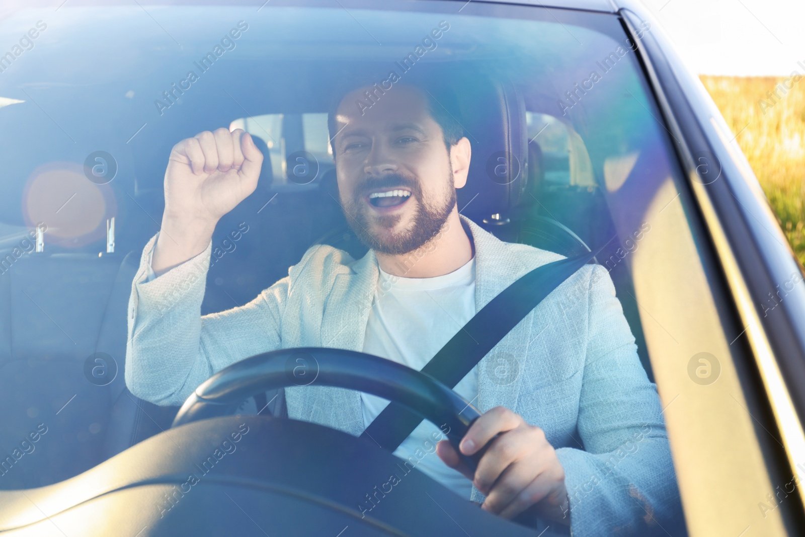 Photo of Man singing in car, view through windshield