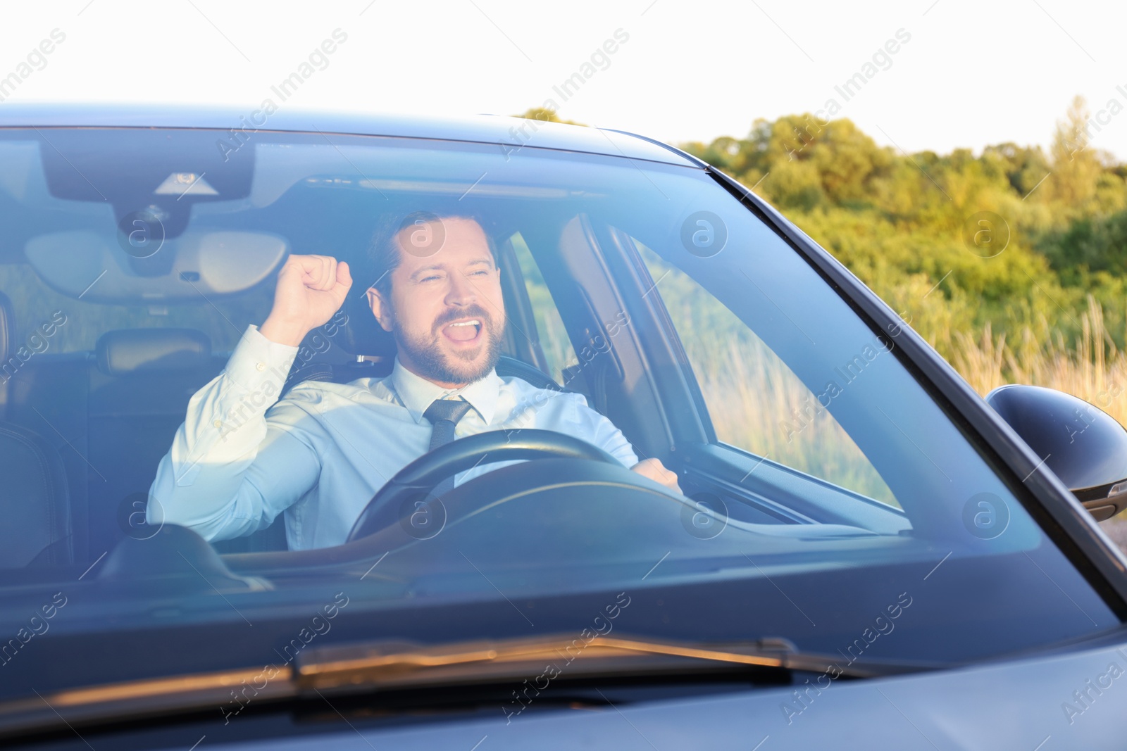 Photo of Man singing in car, view through windshield