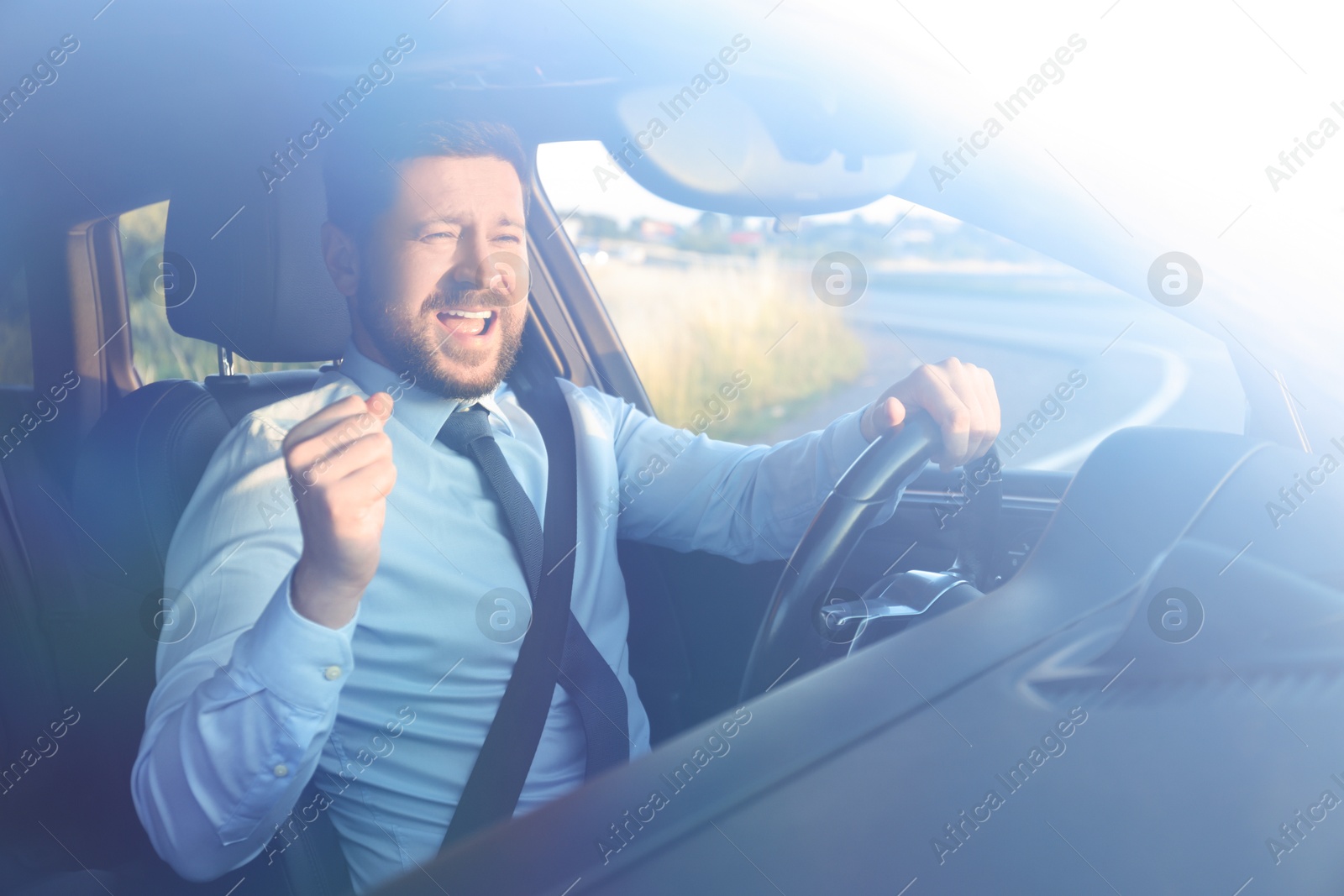 Photo of Man singing in car, view through windshield