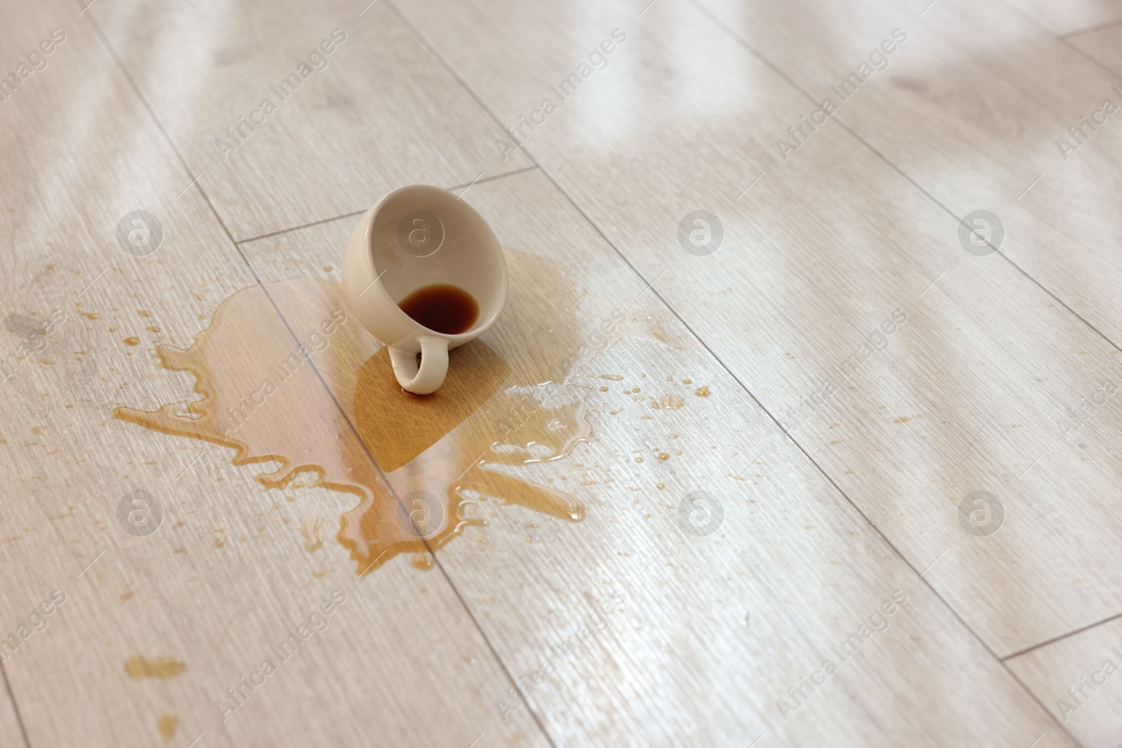 Photo of Cup with spilled drink on wooden floor. Space for text