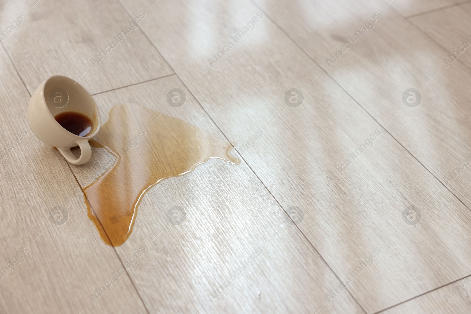 Photo of Cup with spilled drink on wooden floor. Space for text