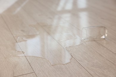 Photo of Glass with spilled drink on wooden floor