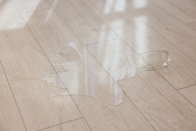 Photo of Glass with spilled drink on wooden floor