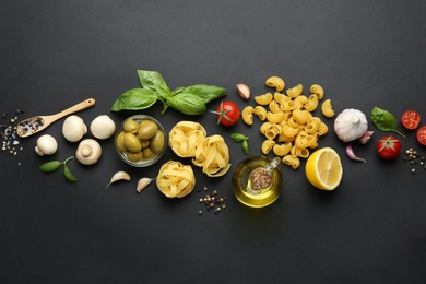 Photo of Different types of pasta, spices and products on black background, flat lay