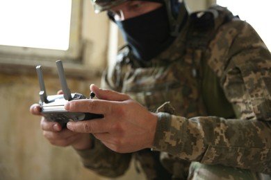 Photo of Military mission. Soldier in uniform with drone controller inside abandoned building, selective focus