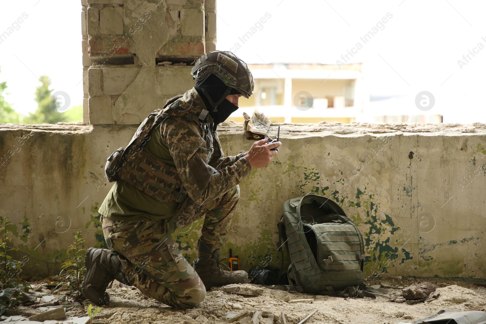 Photo of Military mission. Soldier in uniform with drone controller inside abandoned building, space for text