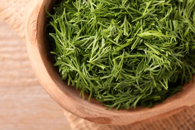 Photo of Fresh cut dill in bowl on wooden table, top view