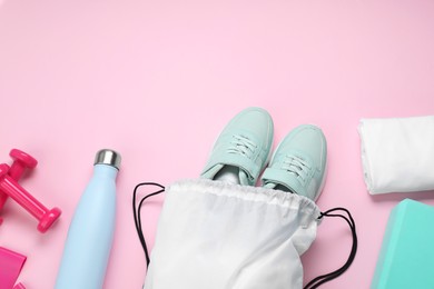 Photo of White drawstring bag, sneakers and sports equipment on pink background, flat lay. Space for text