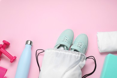 White drawstring bag, sneakers and sports equipment on pink background, flat lay. Space for text