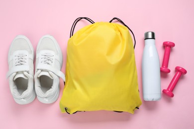 Photo of Yellow drawstring bag, sneakers, thermo bottle and dumbbells on pink background, flat lay