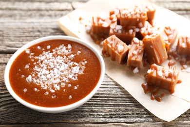 Photo of Caramel sauce with sea salt in bowl on wooden table, closeup