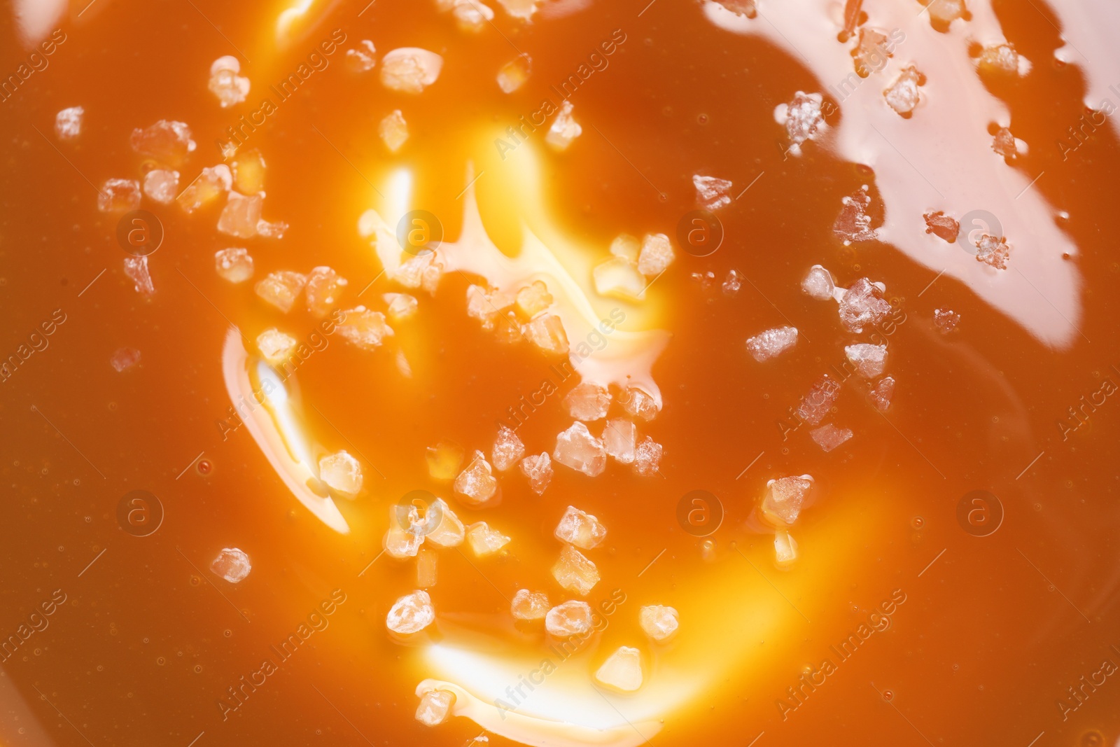 Photo of Delicious caramel sauce with sea salt as background, top view