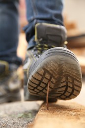 Photo of Careless worker stepping on nail in wooden plank outdoors, closeup