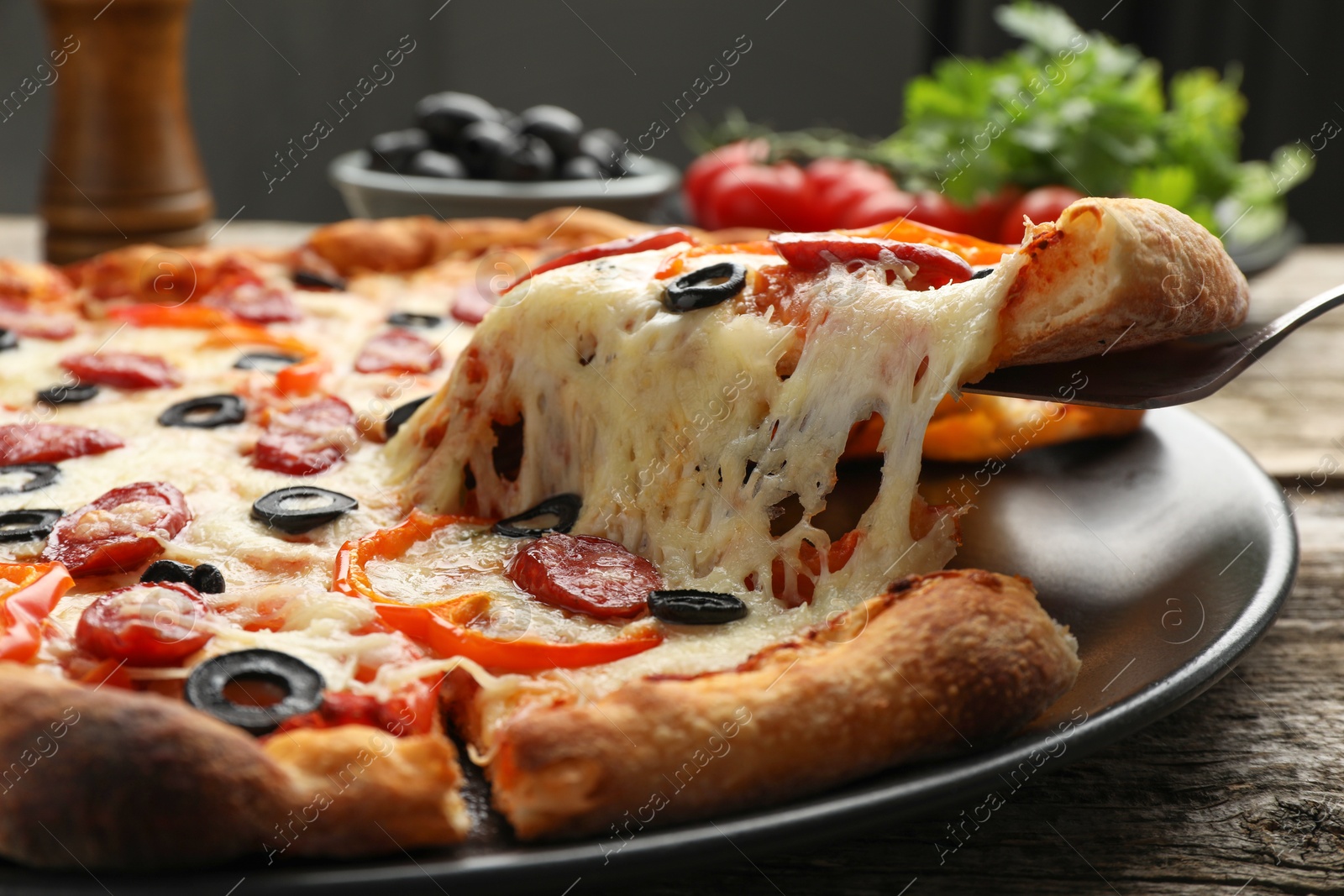 Photo of Taking piece of tasty pizza at wooden table, closeup