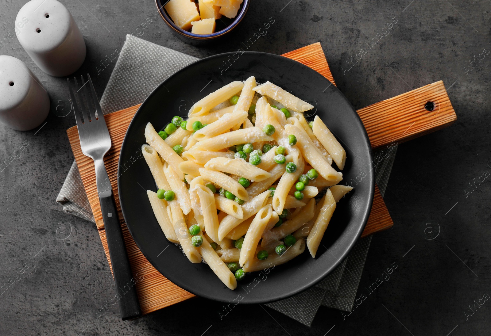 Photo of Delicious pasta with green peas, cheese and fork on grey table, top view